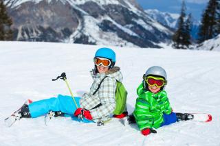 Kinder sitzen mit Skiern auf der Piste Kinder sitzen mit Skiern auf der Piste